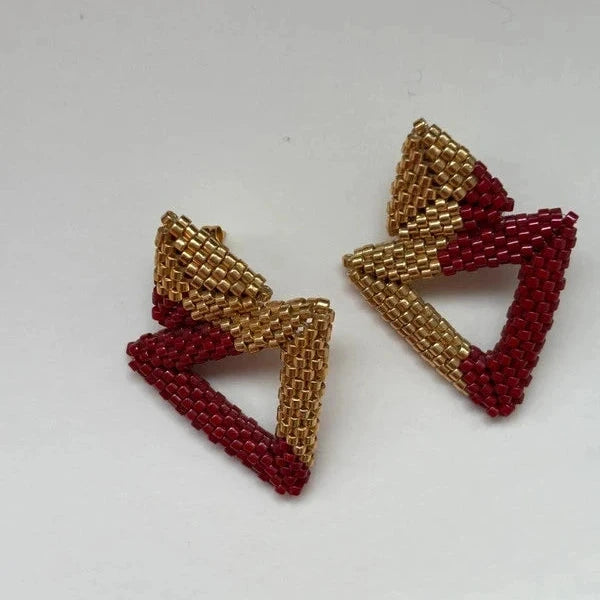 Pair of triangle-shaped earrings with gold and red beads on a white background