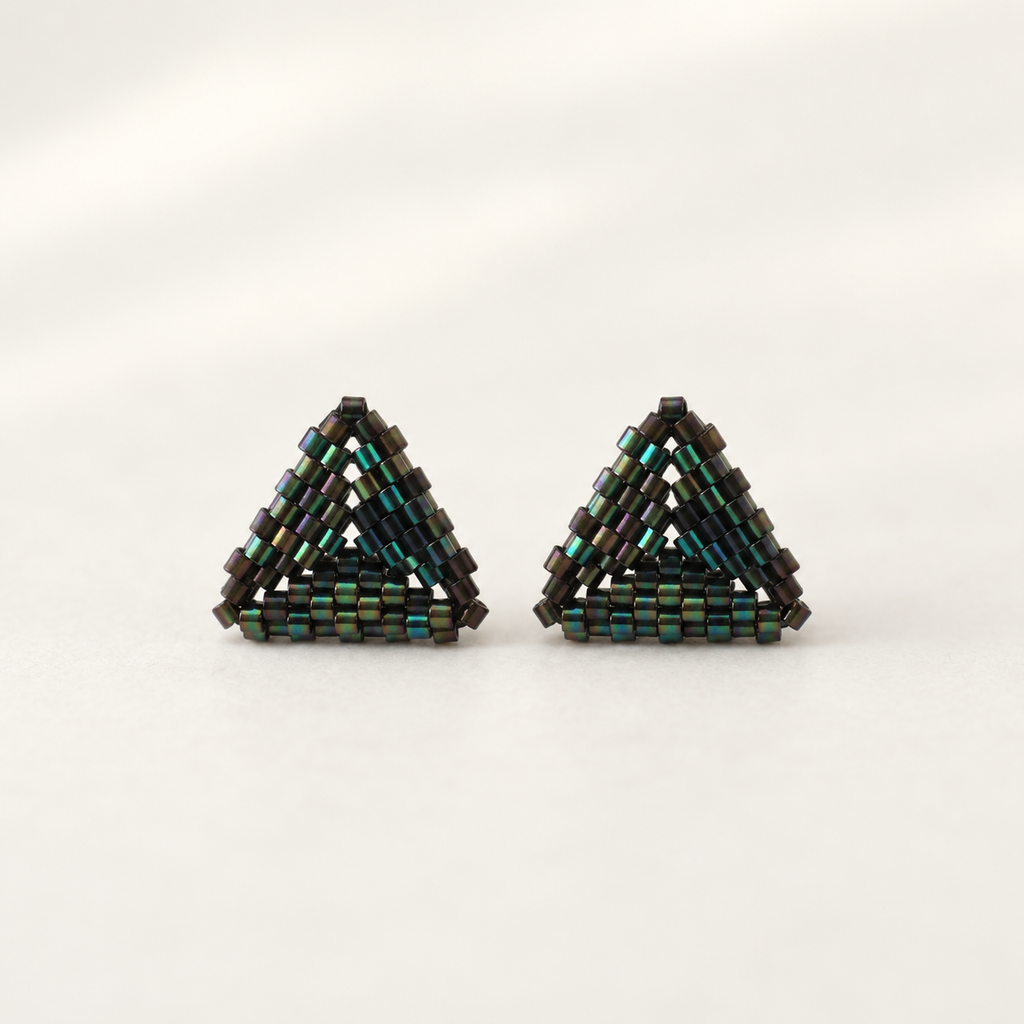A pair of handmade triangular beaded earrings made from small dark metallic beads with iridescent green and blue reflections, set against a plain light background.