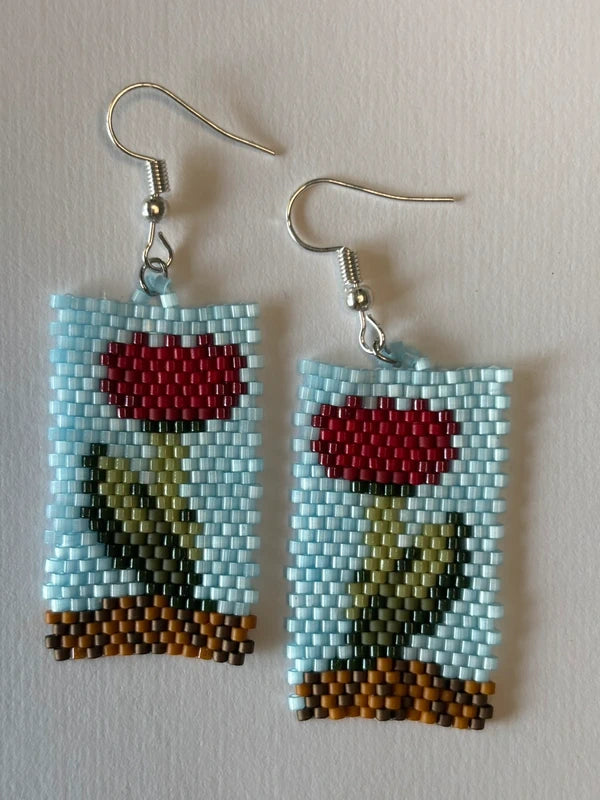 Pair of beaded earrings with a rose design on a light background