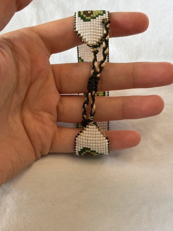 Hand holding a small beaded heart-shaped object on a light background