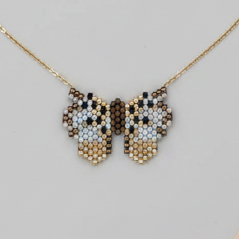 Butterfly-shaped necklace with beaded details on a light gray background