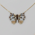 Butterfly-shaped necklace with beaded details on a light gray background