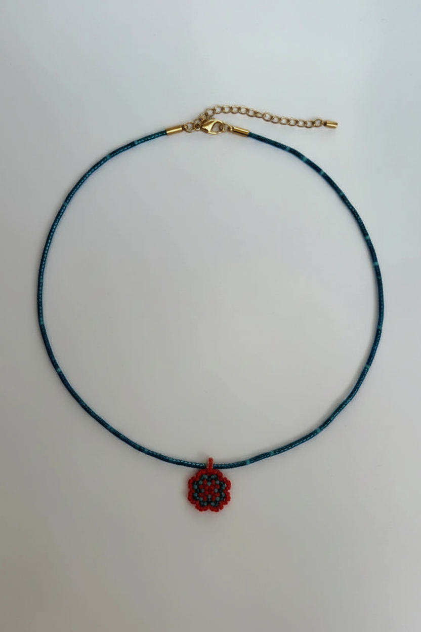 Necklace with a blue cord and red pendant on a white background