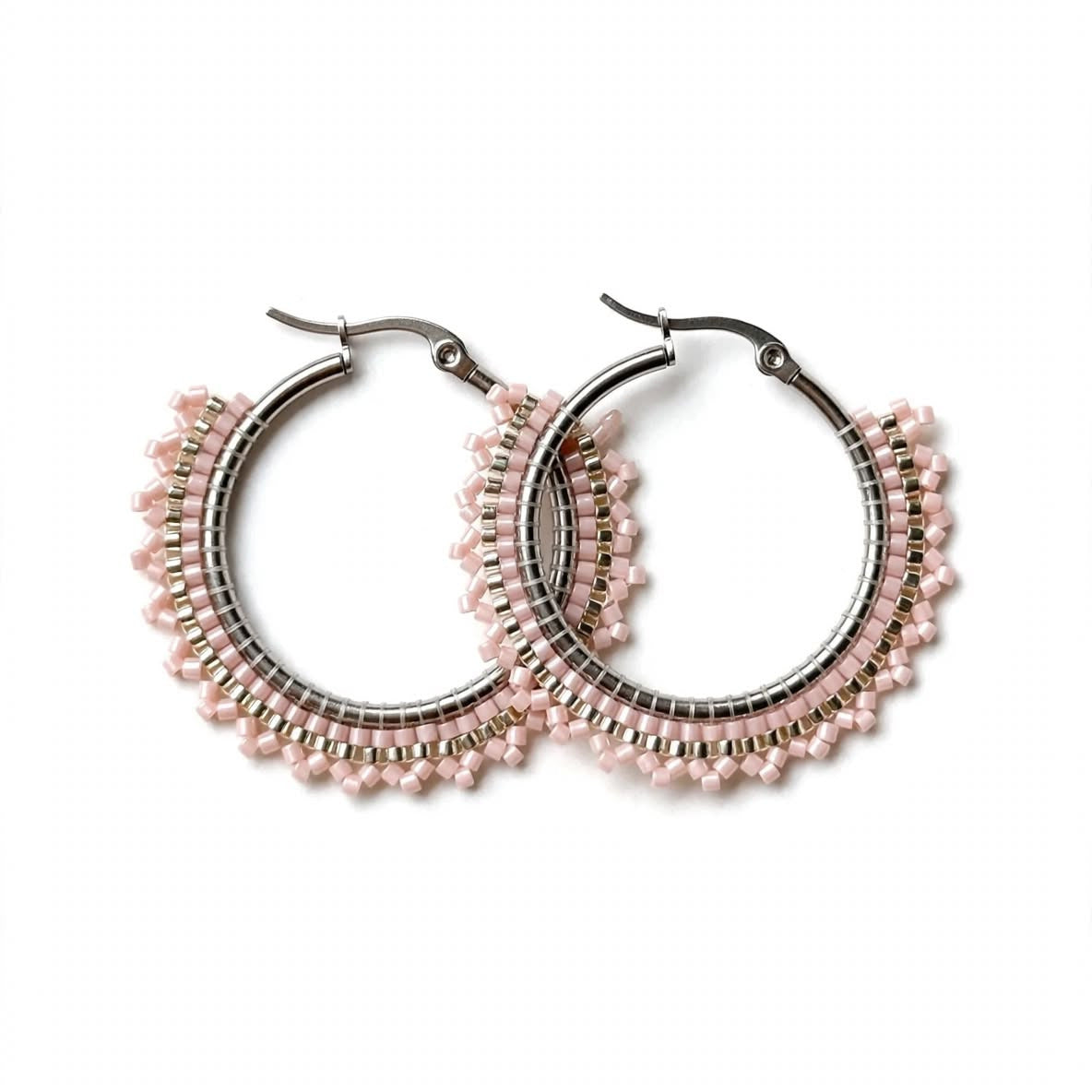 A pair of silver-tone hoop earrings adorned with rows of small light pink beads, displayed against a solid white background.