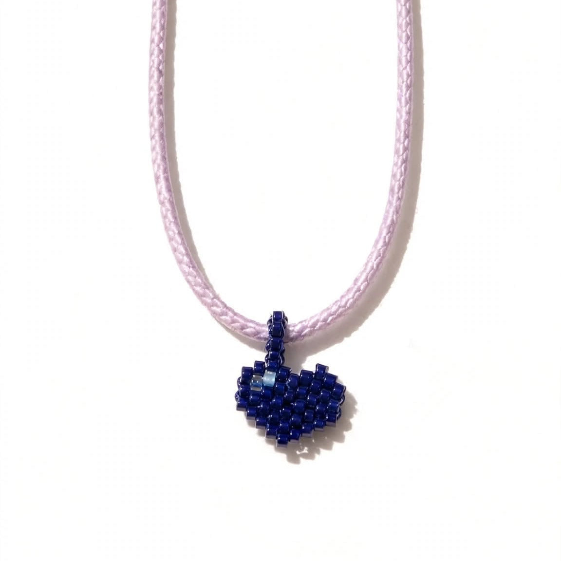 A light pink braided cord necklace featuring a small, handcrafted heart-shaped pendant made of dark blue seed beads, shown against a plain white background.