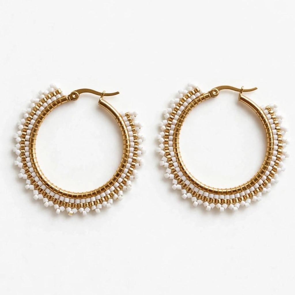 A pair of gold hoop earrings adorned with multiple rows of small white pearls, displayed on a clean white background.