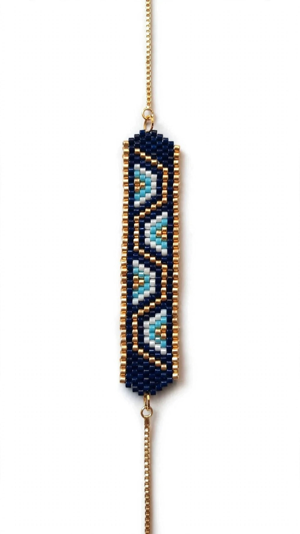 A beaded geometric stretch bracelet featuring a navy blue base with light blue and gold patterned accents, suspended from a gold chain on a white background.