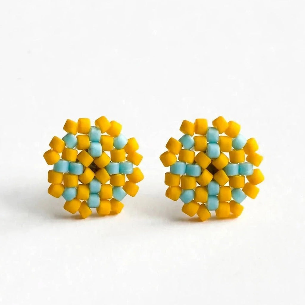 A pair of handmade beaded stud earrings with a geometric pattern of yellow and light blue beads, displayed on a clean white background.