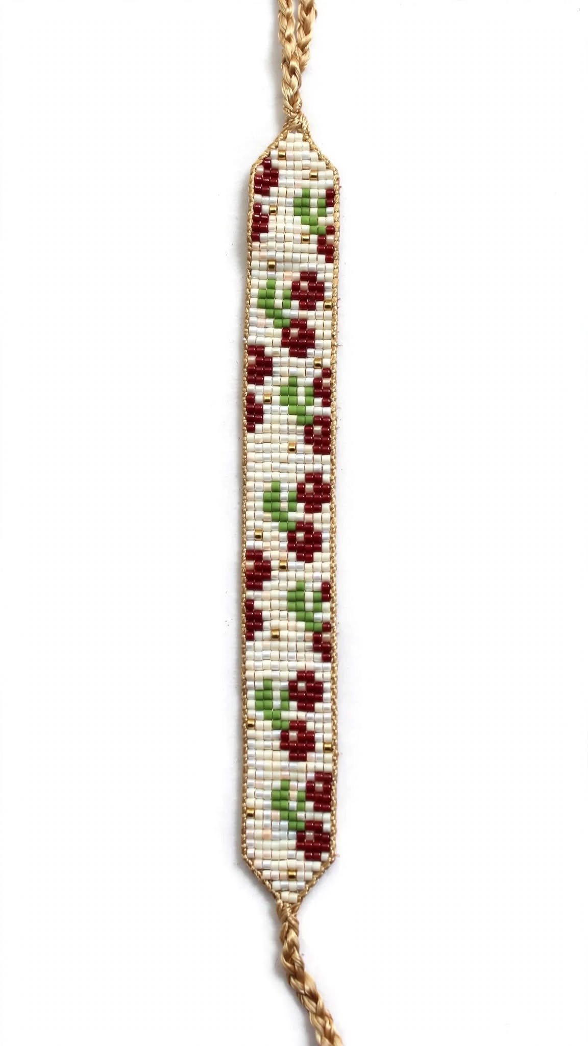 A beaded floral wristlet or bracelet featuring a vertical rectangular body with a pattern of red flowers and green leaves on a white beaded background, finished with a braided gold-toned chain at the top and bottom, shown against a plain white background.