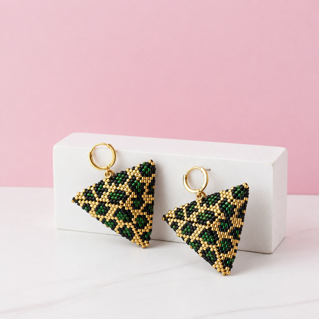 Triangular beaded earrings on a white stand with a pink background