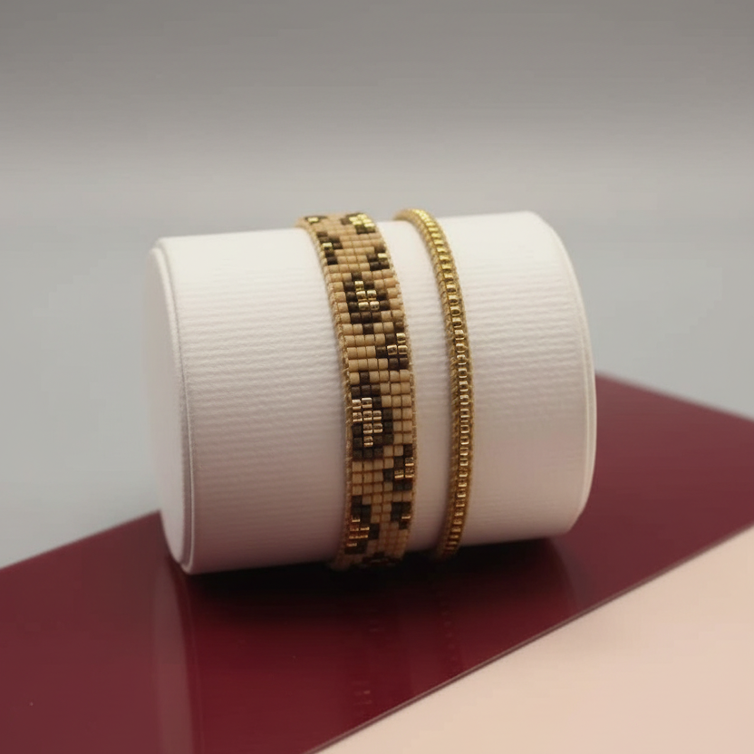 Gold beaded bracelet on a white cylindrical container with a gradient background
