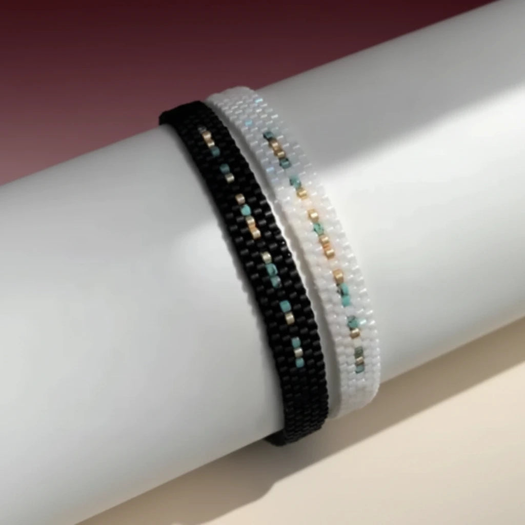 Close-up of a wrist wearing two beaded bracelets on a neutral background