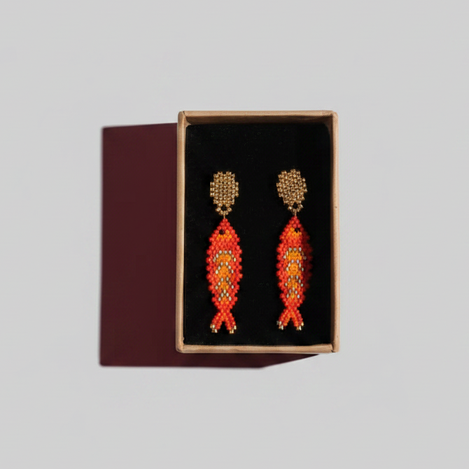 Pair of orange beaded earrings in a black box on a gray background