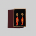 Pair of orange beaded earrings in a black box on a gray background