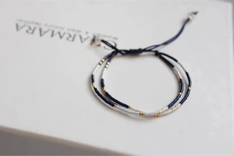 Bracelet with blue and gold beads on a white surface with 'ARMARA' branding.