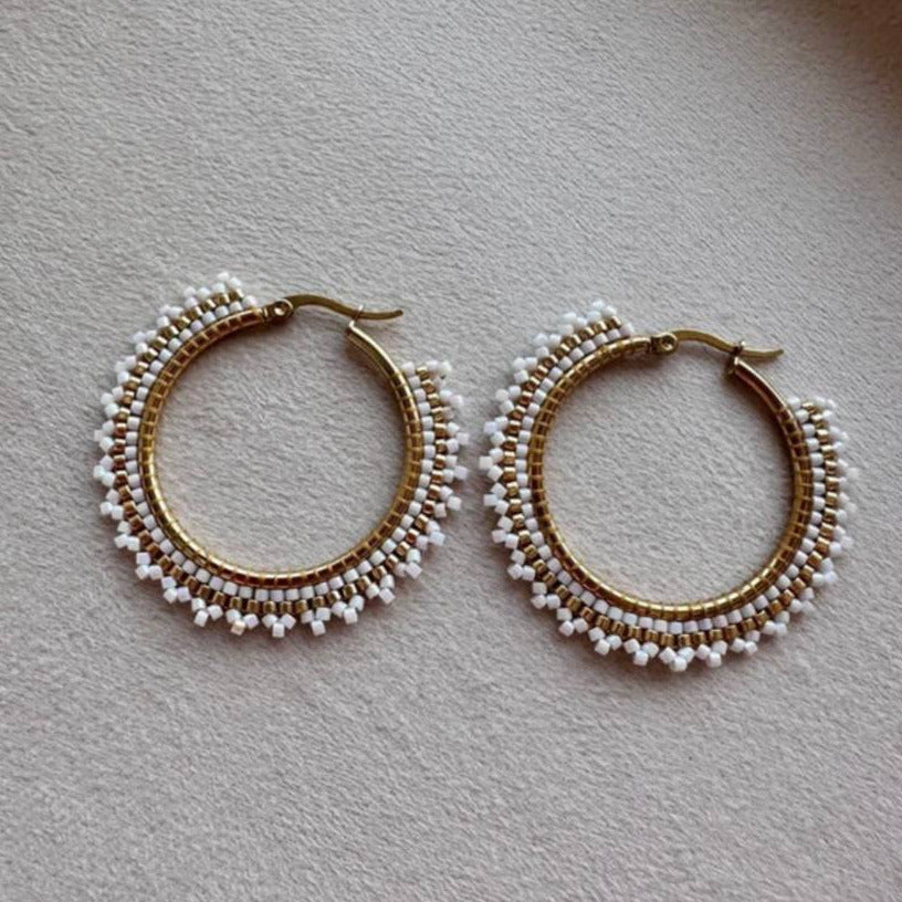 Pair of gold hoop earrings with bead detailing on a light gray surface